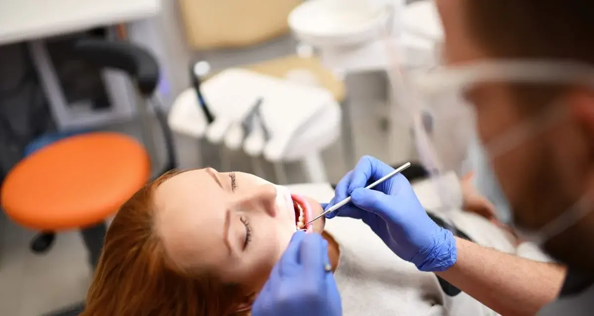 Pacjentka z rudymi włosami u dentysty. Badanie jamy ustnej, które może być związane z diagnostyką twardziny układowej.