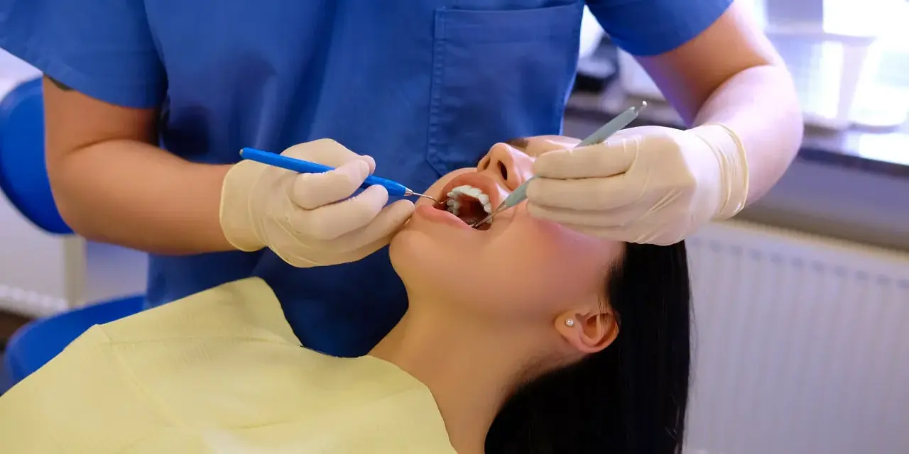 Dentysta wykonuje fluoryzację zębów pacjentki, dbając o ich zdrowie i ochronę przed próchnicą.