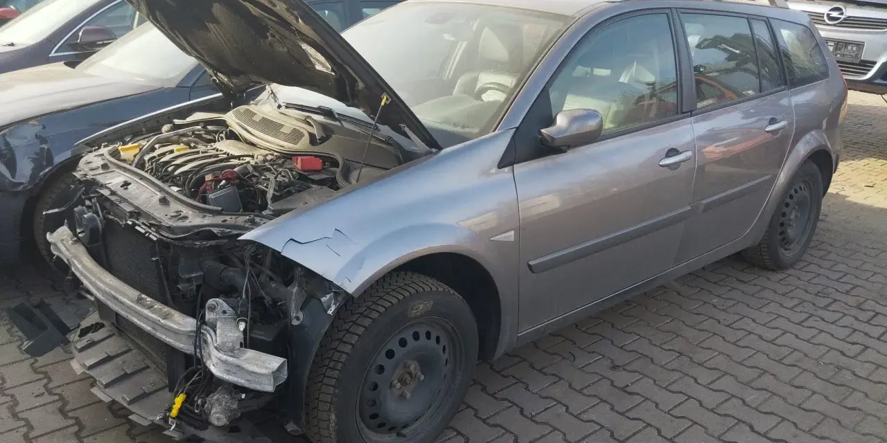 Szary kombi z otwartą maską, widoczny silnik i uszkodzony przód. Idealny, by dowiedzieć się, jak sprzedać auto na części.