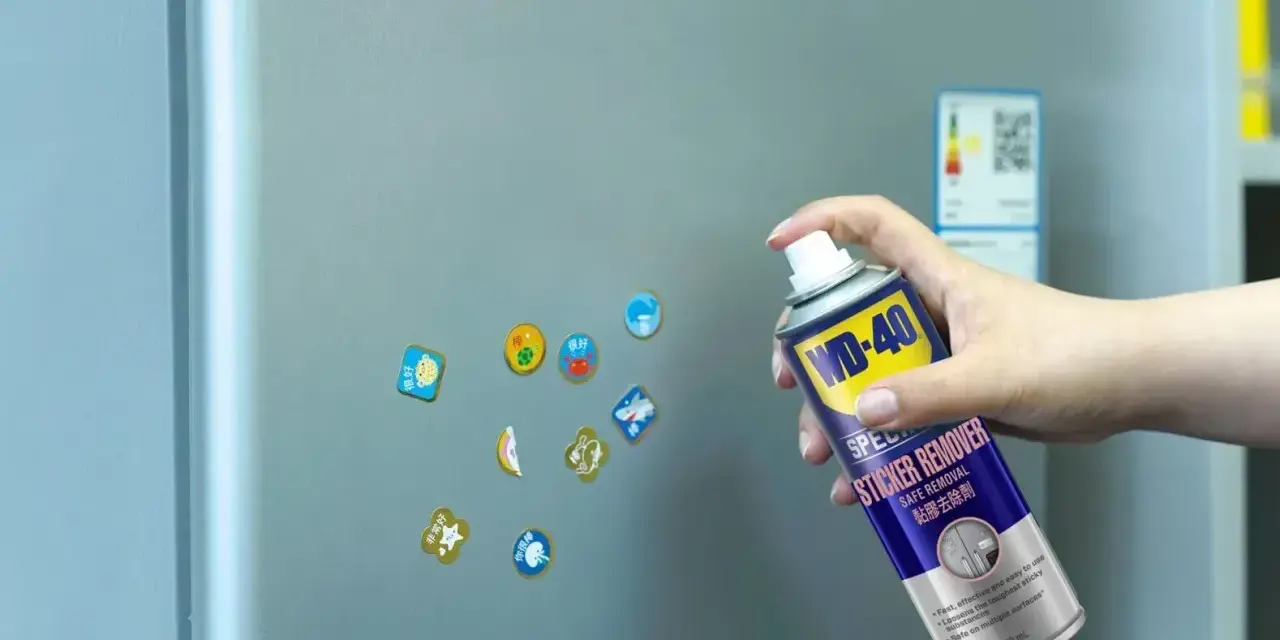 Jak usunąć naklejkę z szyby? Puszka WD-40 Sticker Remover w dłoni, gotowa do działania na lodówce.