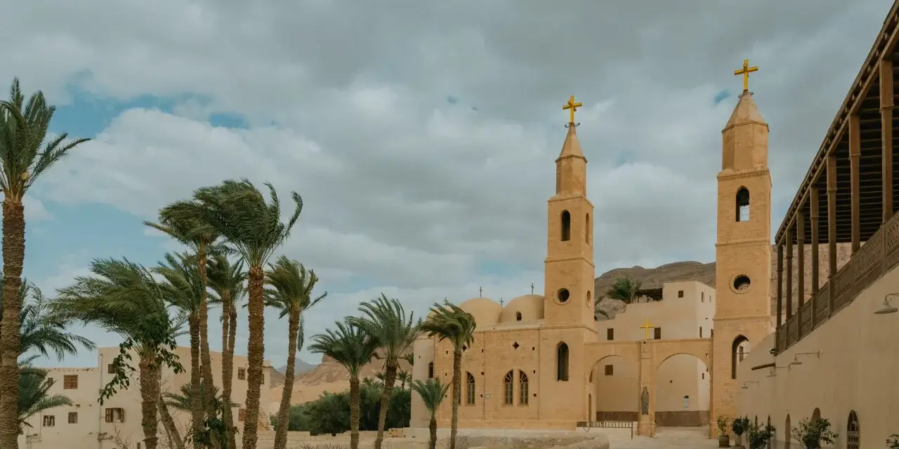 A monastery courtyard with palm trees and a bell tower, evoking the spirit of the desert fathers and mothers.
