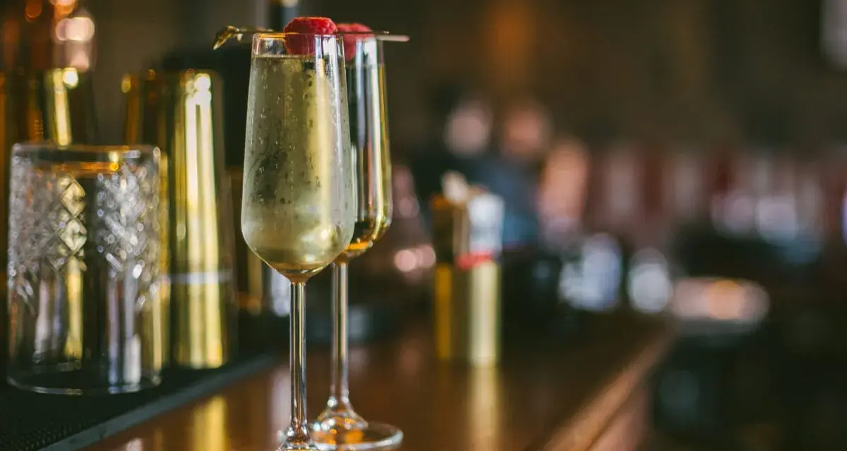 Dwa kieliszki musującego drinka z maliną na wierzchu. Idealne na domowe przyjęcie, inspiracja do drinki przepisy domowe.