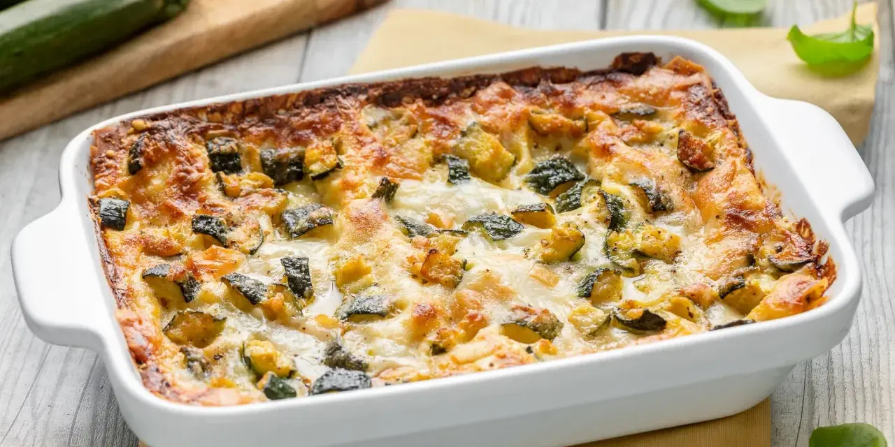 Lasagne di zucchine appena sfornate, dorate e filanti, con zucchine a cubetti e formaggio fuso.