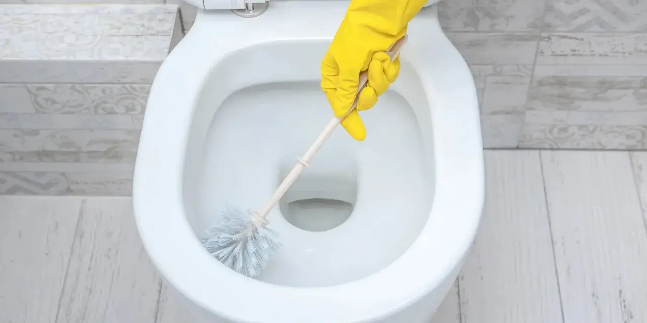 Main jaune pour nettoyer les toilettes.