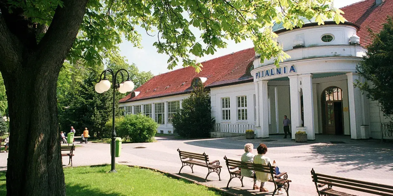 Uzdrowiska na Dolnym Śląsku: Pijalnia wód w otoczeniu zieleni, z ławkami dla kuracjuszy.