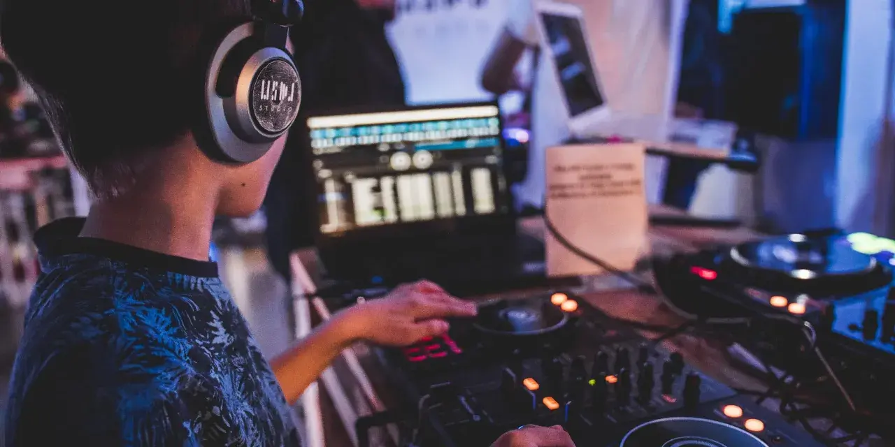 Młody DJ ćwiczy na sprzęcie, słuchawki na uszach. To świetny moment na rozpoczęcie kursu DJ online i naukę miksowania.