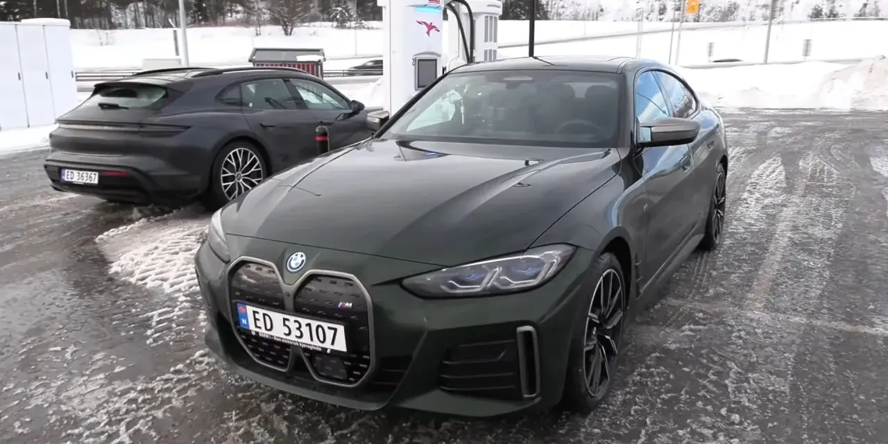 Zielony BMW i4 na ładowarce. W tle ciemny Porsche Taycan. Dane techniczne BMW i4 interesują wielu.