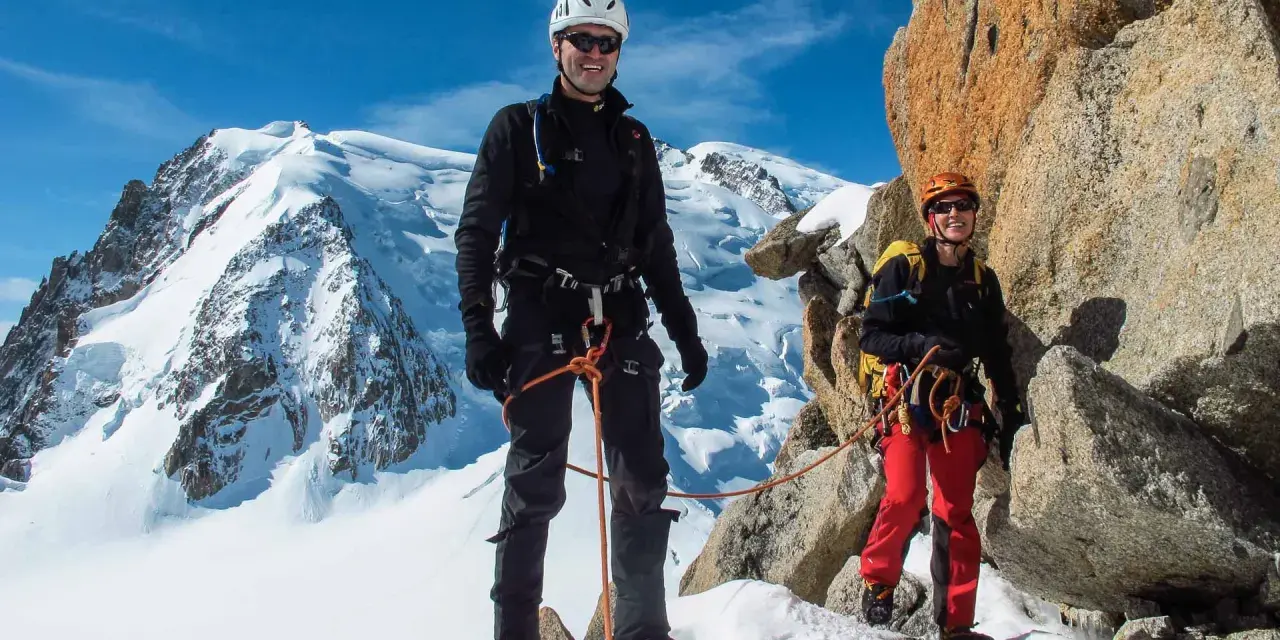 Zwei Bergsteiger auf dem Weg zur Mont Blanc Besteigung, umgeben von Schnee und Felsen.