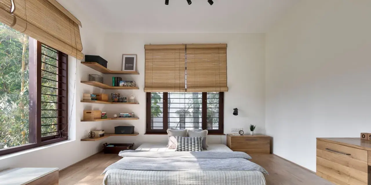 Habitación con cama baja, estanterías de madera y persianas de bambú. Un ejemplo de estilos de habitaciones minimalistas y acogedoras.