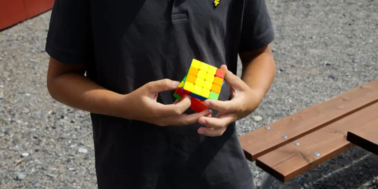 Ungdom med en färgglad Rubiks kub i händerna, redo för rubiks kub speed.