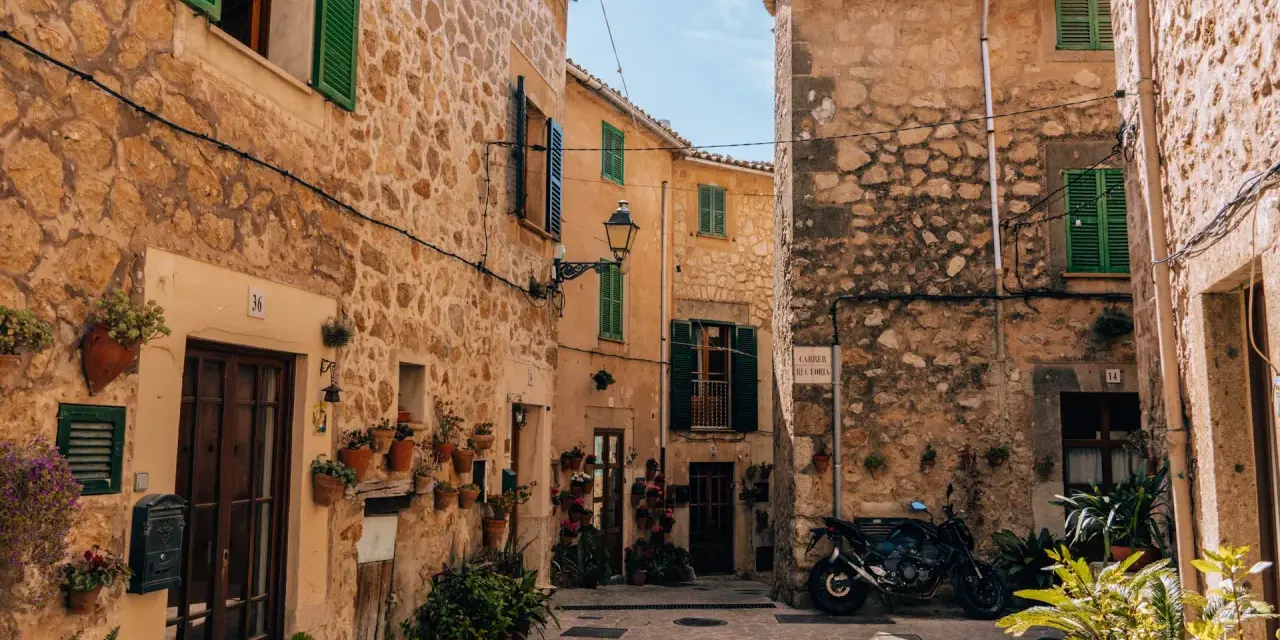 Urokliwa uliczka w Valldemossa. Zobacz kamienne domy z zielonymi okiennicami i mnóstwo kwiatów. Idealne miejsce na spacer i odkrywanie uroków miasteczka.