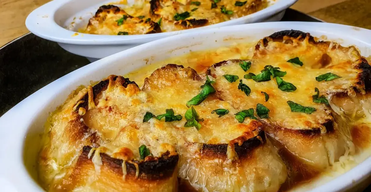 Deux gratins de soupe à l'oignon, dorés et gratinés, prêts à être dégustés. Une recette réconfortante.