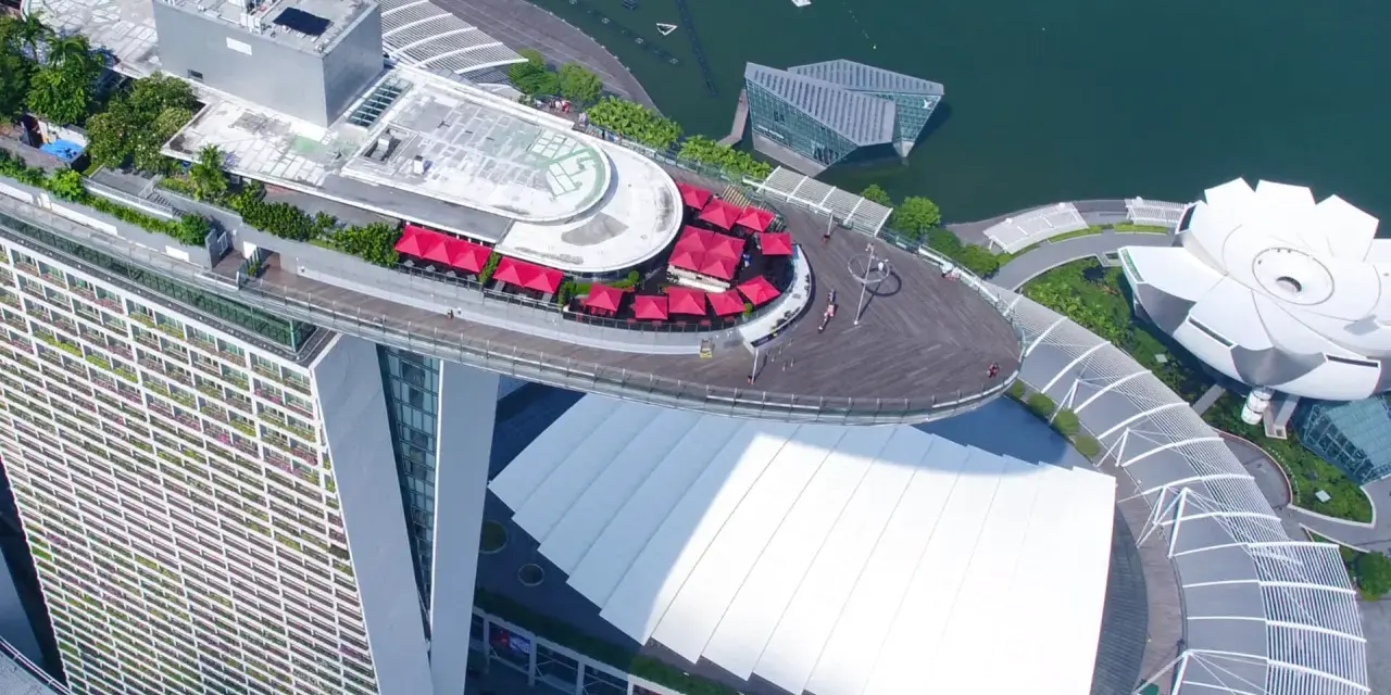 Widok z lotu ptaka na słynny singapur hotel statek z czerwonymi parasolami i basenem na dachu.