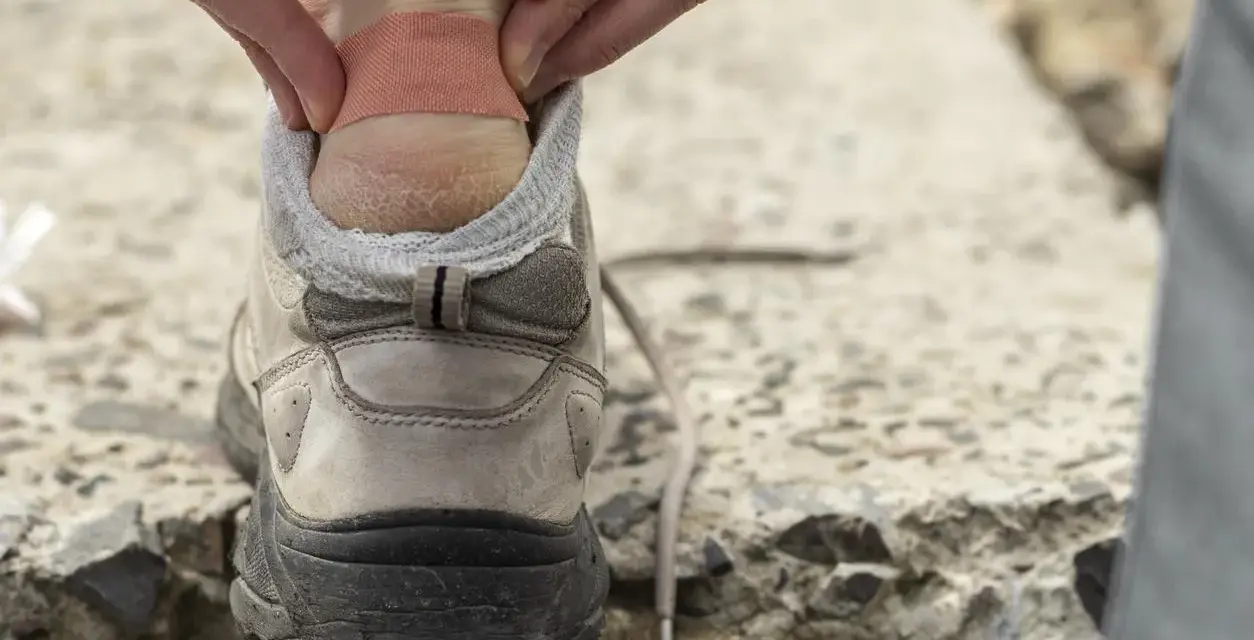 Application d'un pansement sur une ampoule au talon, une étape clé pour savoir comment soigner une ampoule au pied et continuer sa marche.