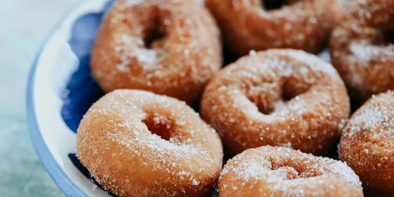 Rosquillas caseras de toda la vida, doradas y espolvoreadas con azúcar, listas para disfrutar.