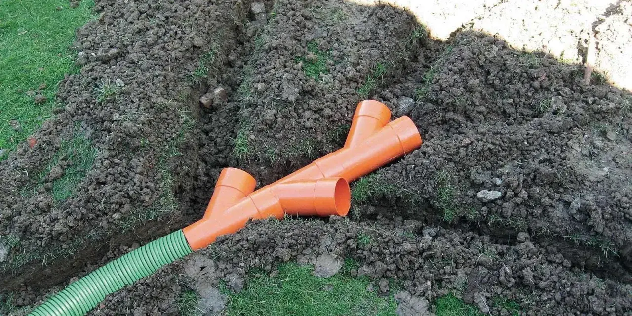 Tubi arancioni a Y e un tubo verde in una trincea: il sistema per capire come drenare il terreno.