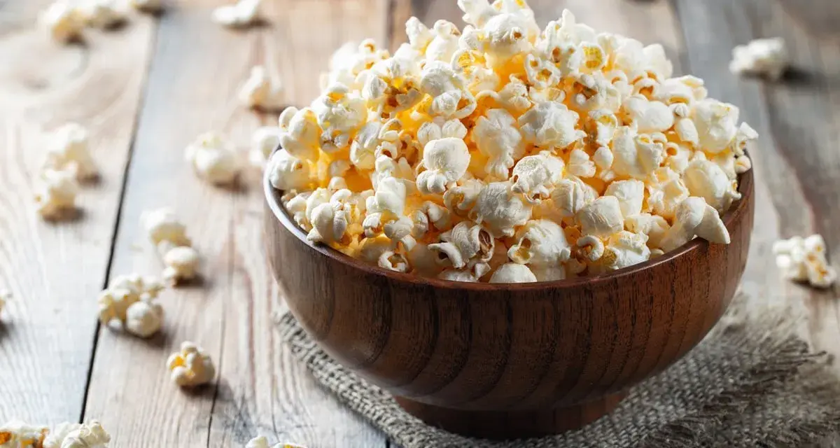 Pyszny popcorn w drewnianej misce, idealny na wieczór filmowy. Zastanawiasz się nad popcorn kcal?