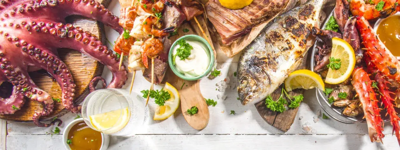 Un'abbondante grigliata di pesce con polpo, gamberi, calamari, aragosta e pesce intero, guarnita con limone e prezzemolo.