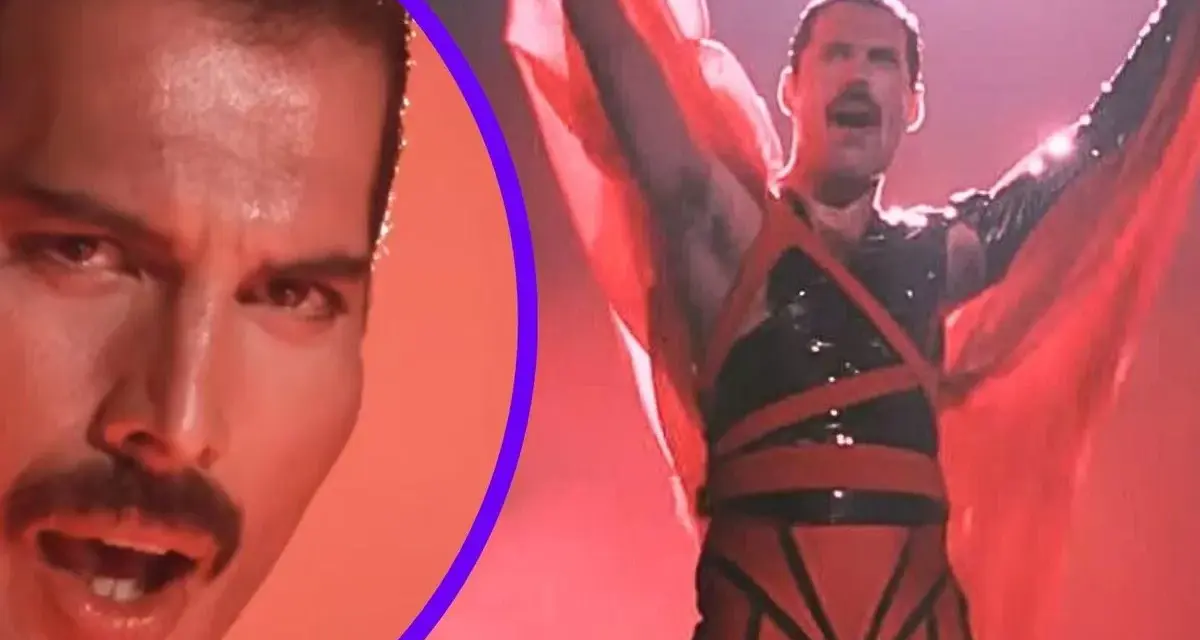 Freddie Mercury w czerwonym stroju, z rękami w górze, promuje swój **freddie mercury solo album**. Obok jego twarz z charakterystycznym wąsem.