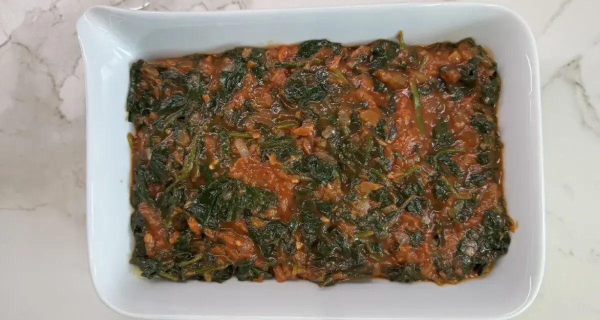 Lasaña de espinacas en salsa de tomate en un plato blanco.
