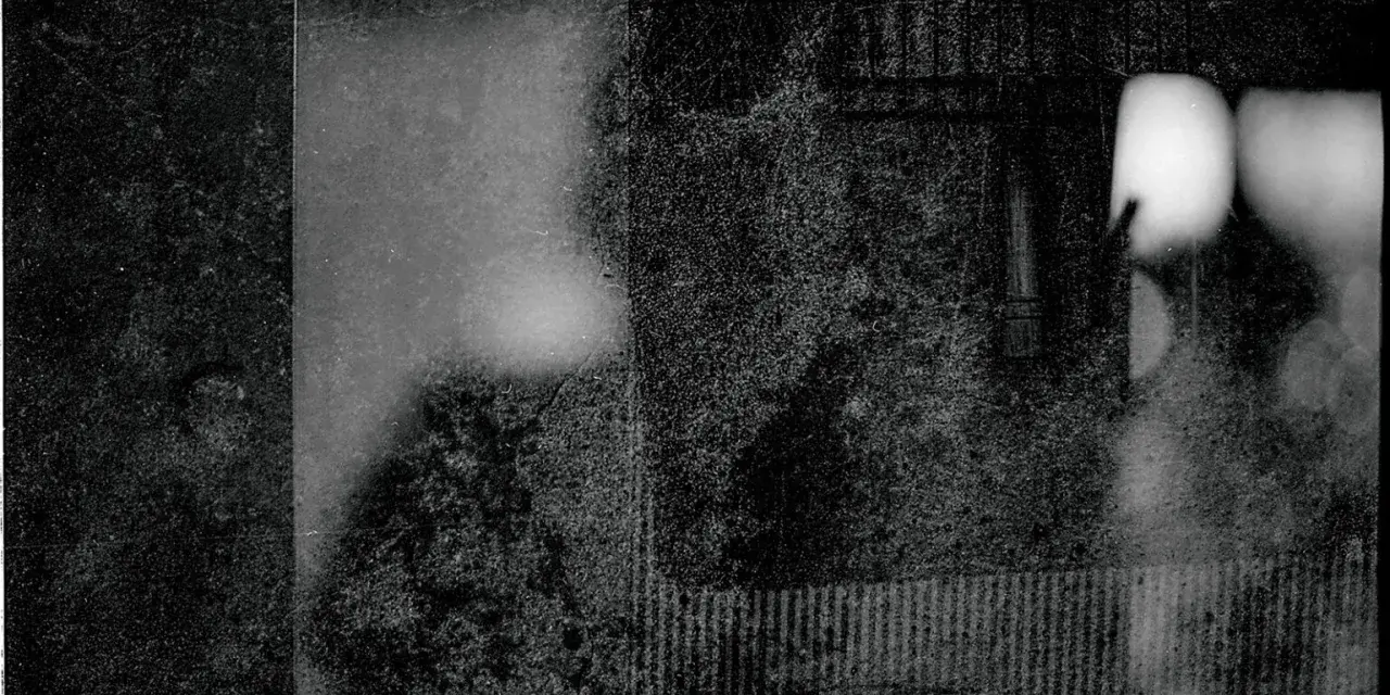 Mroczna, ziarnista fotografia. Widać fragmenty twarzy, być może portret autorstwa Mariusza Gajewskiego, z rozmytymi światłami i teksturami.