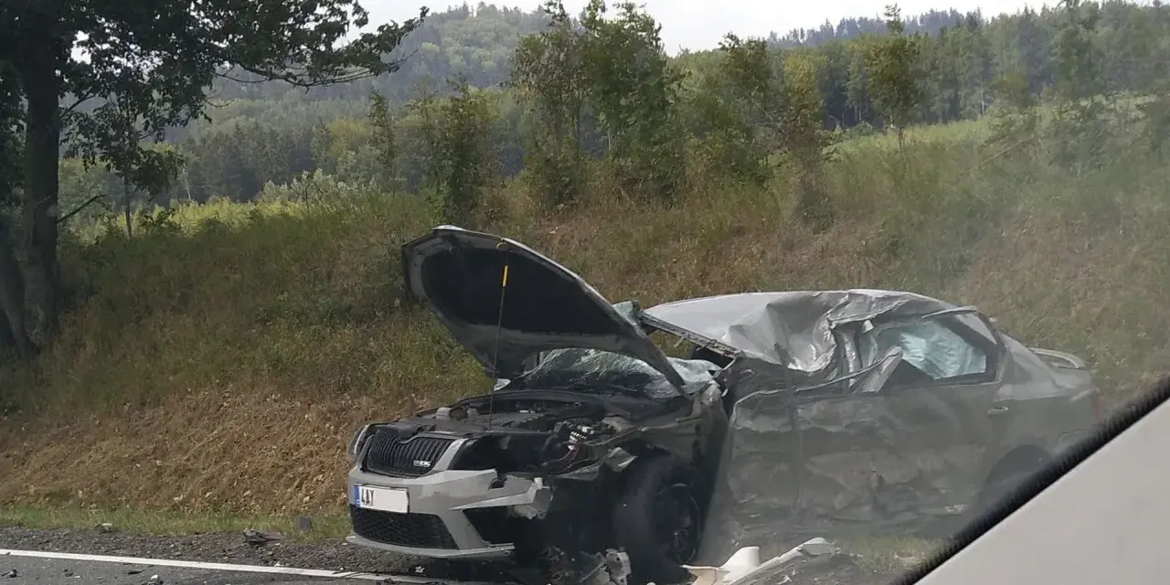 Zniszczony samochód po wypadku, maska otwarta, widoczne uszkodzenia. DKL rejestracja widoczna na przodzie pojazdu.