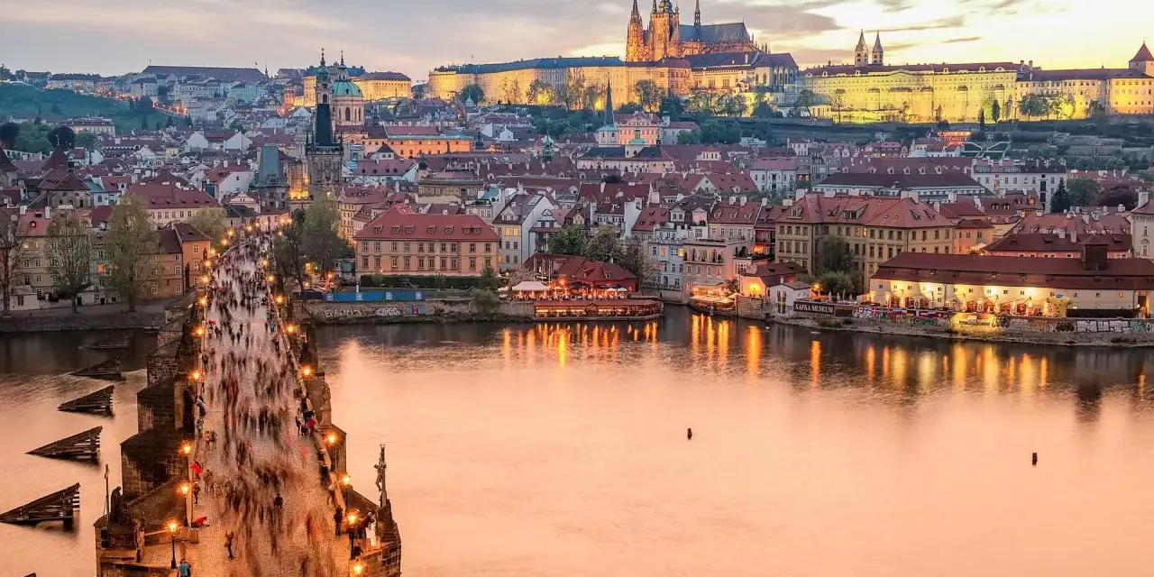 Zachód słońca nad Pragą, tłumy na Moście Karola. Czy do Czech trzeba mieć paszport? Nie, wystarczy dowód osobisty.