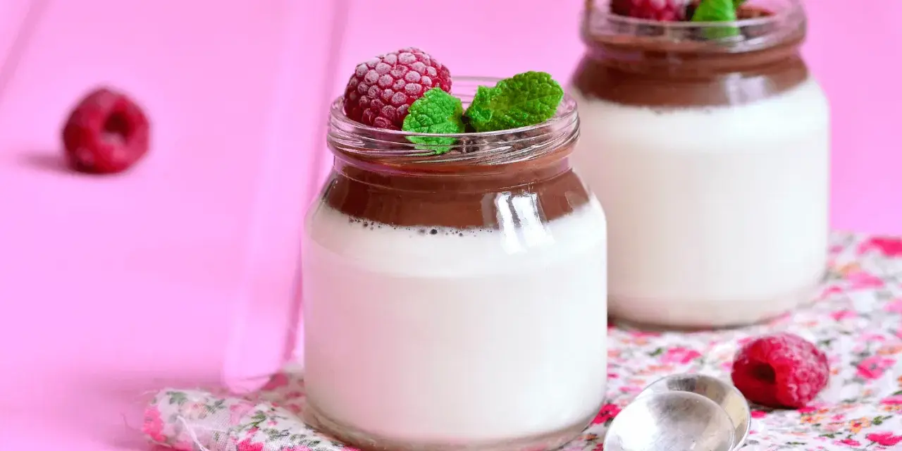 Två glas med choklad- och vaniljpannacotta, toppade med hallon och mynta. Perfekt som dessertvin till pannacotta.