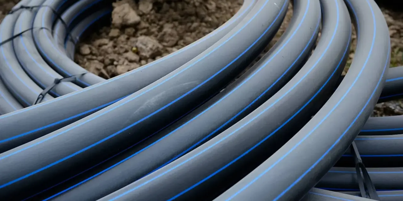 Coiled black hdpe plastic pipes with blue stripes, ready for installation.