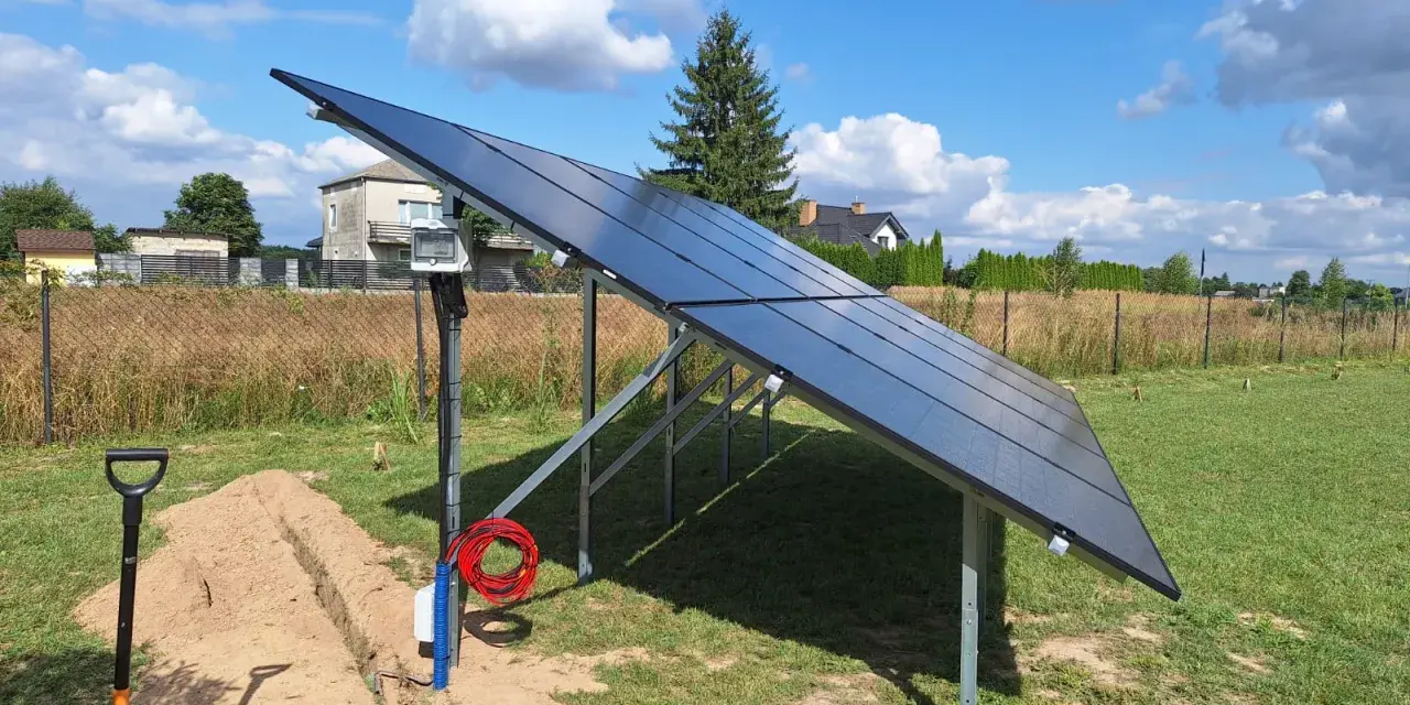 Nowa instalacja fotowoltaiczna w granicy działki, gotowa do podłączenia. Obok koparka i materiały.