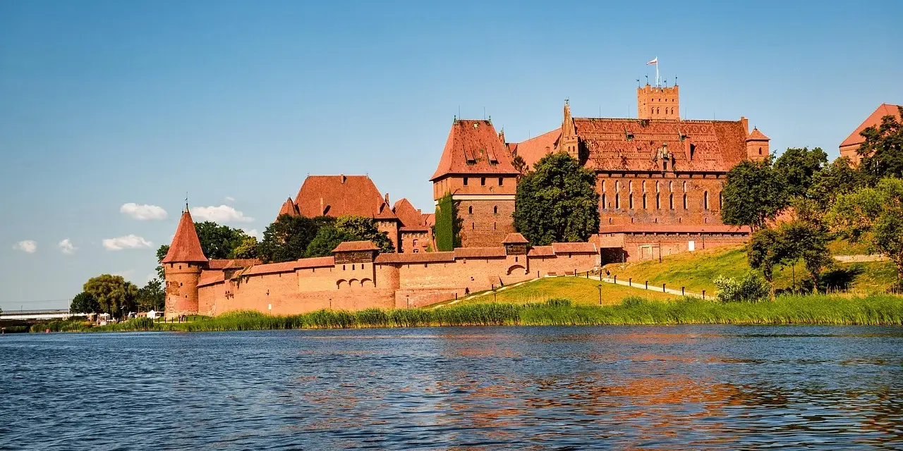 Potężny zamek w Malborku nad rzeką. Zwiedzanie zamku w Malborku to podróż w czasie.