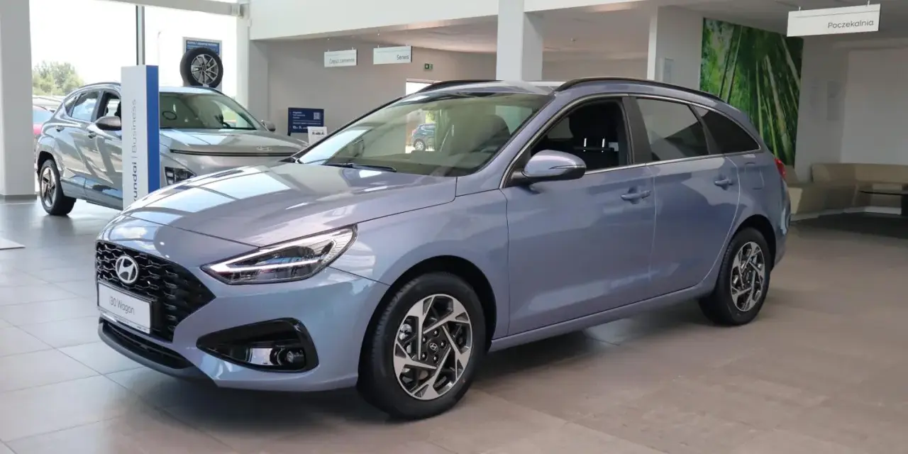 Niebieski Hyundai i30 Wagon z 2015 roku stoi w salonie samochodowym.