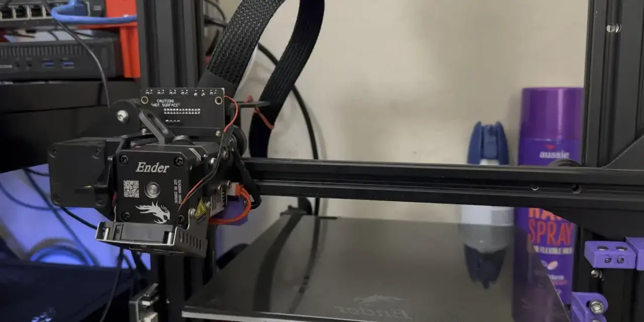 Głowica drukująca klipper ender 3 z kablem w oplocie. Na półce w tle fioletowa puszka z napisem "aussie".