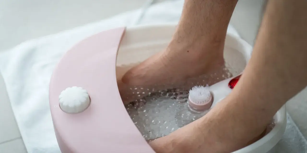 Soaking feet in warm water with salt benefits relaxation and skin softening. A foot spa with a brush is used.