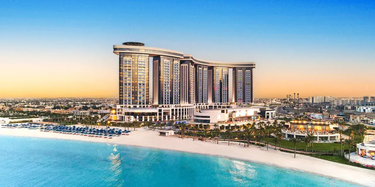 Luksusowy Rixos Premium Alamein z widokiem na turkusowe morze i piaszczystą plażę. Idealne miejsce na wakacje.