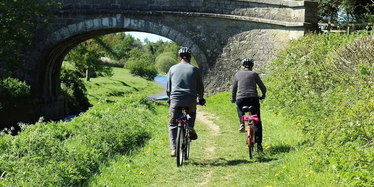 Dwie osoby na rowerach pod kamiennym mostem, cieszą się pięknymi ścieżkami rowerowymi lubuskimi.