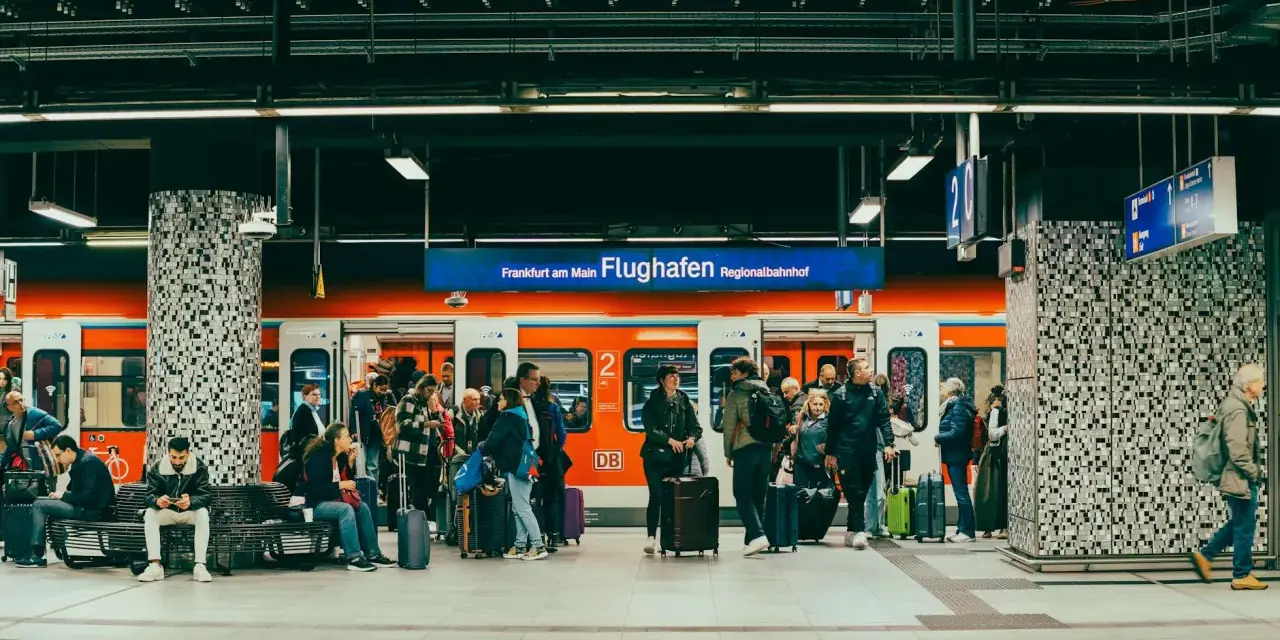 Pasażerowie z bagażami czekają na pociąg na peronie lotniska Frankfurt am Main Flughafen Regionalbahnhof.
