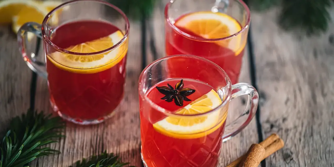 Drei Tassen Kinderpunsch mit Orangenscheiben und Sternanis. Die ideale Temperatur für den Punsch ist warm und einladend.