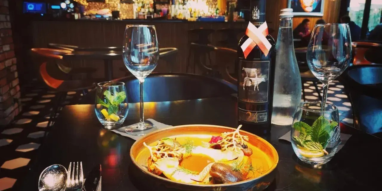 Elegancka kolacja w Nowym Targu. Na stole danie, wino i woda. Idealne miejsce, by dowiedzieć się, gdzie zjeść w Nowym Targu.