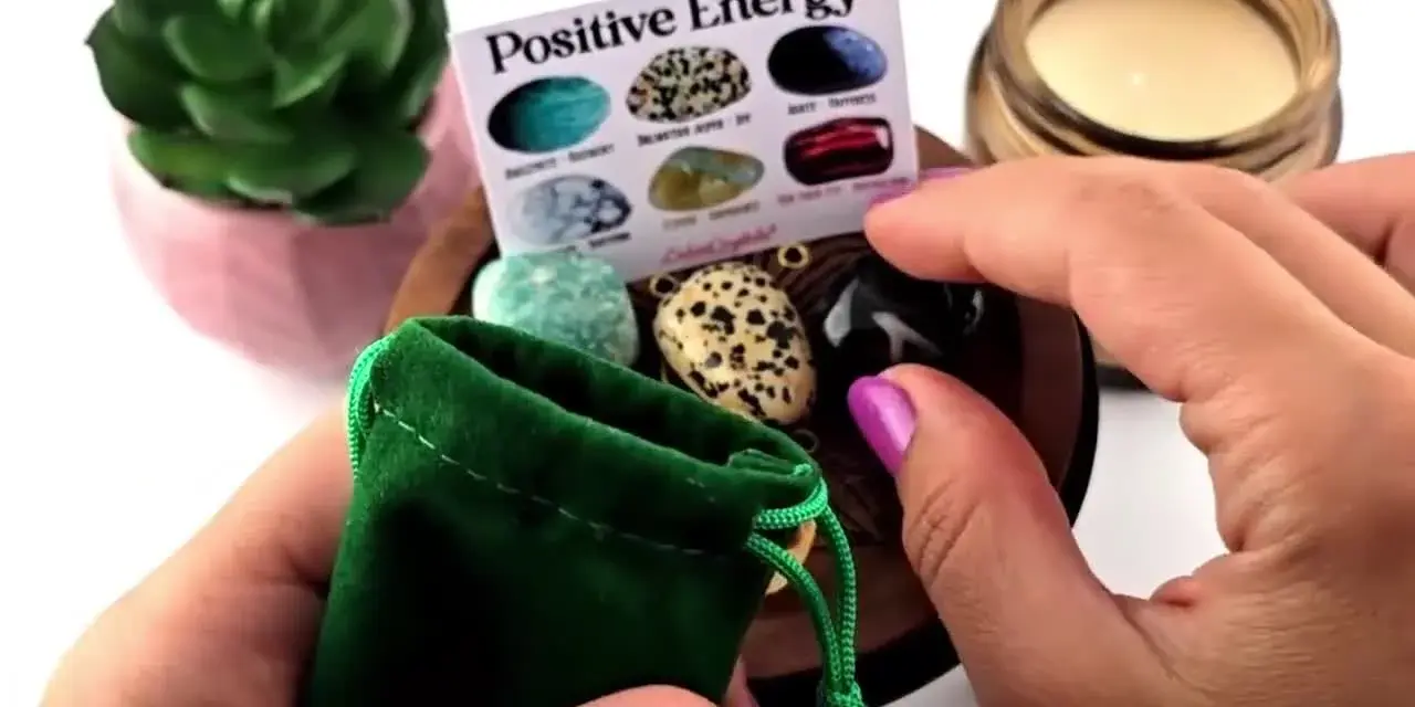 Manos sostienen una bolsa verde con piedras de energía positiva. Un folleto muestra varias piedras.
