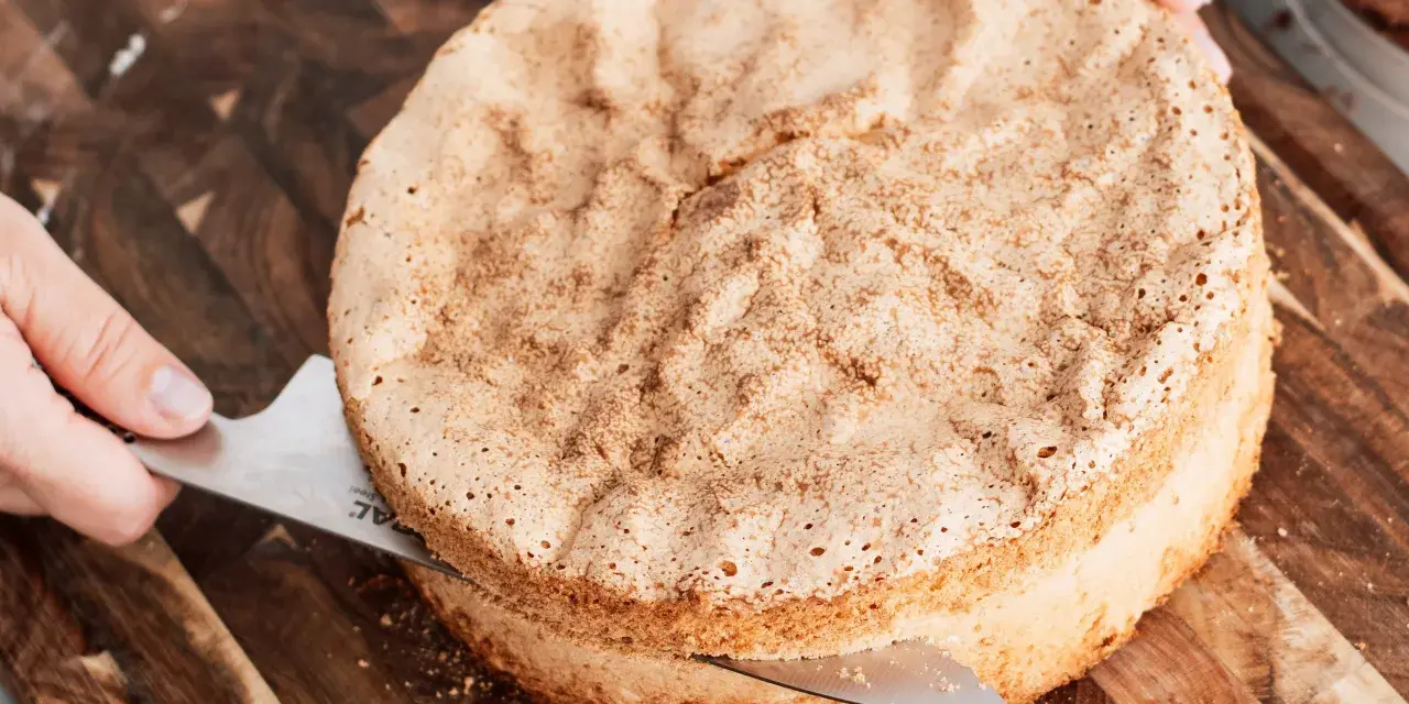 En person skär en fluffig sockerkaksbotten med en kniv. Perfekt för ditt nästa cake recept!