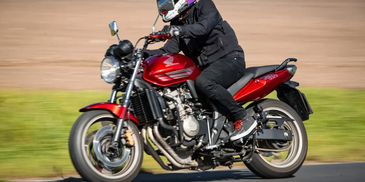 Motocyklista w kasku w stylu Jokera pędzi na czerwonym Honda CBF 600. Dane techniczne tego modelu są imponujące.