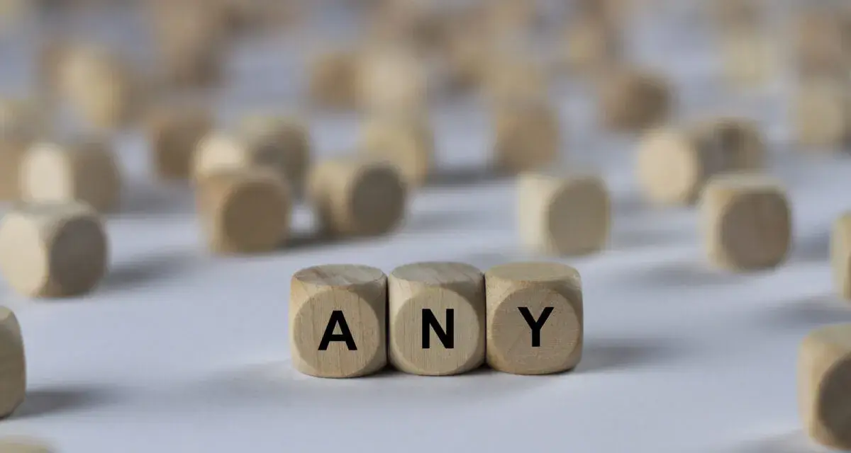 Holzwürfel mit den Buchstaben A, N, Y bilden das Wort "ANY". Sie liegen auf einem hellen Untergrund, umgeben von vielen weiteren unscharfen Würfeln.