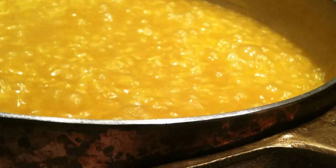 Un cremoso risotto alla milanese che sobbolle in una pentola di rame, pronto per essere gustato.
