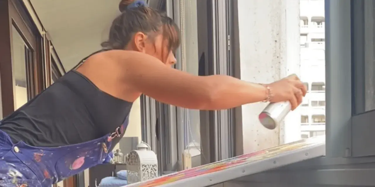 Une artiste applique du vernis sur sa peinture acrylique colorée, protégeant ainsi son œuvre.