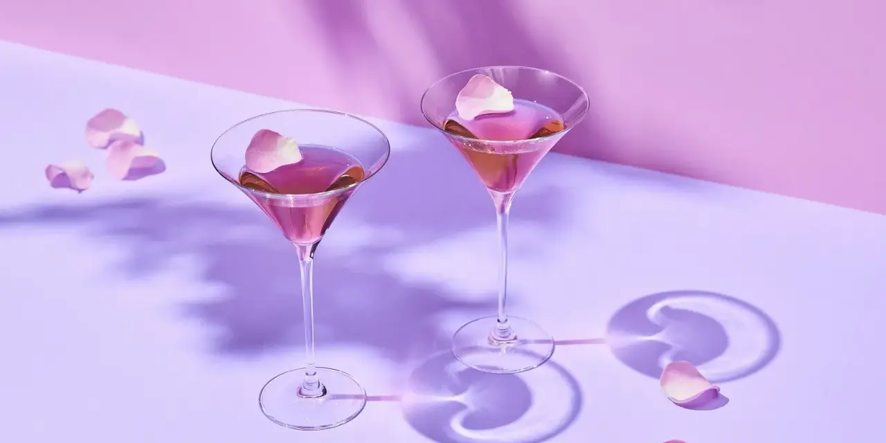 Elegancki French Martini przepis: dwa kieliszki z różowym drinkiem, ozdobione płatkami róż, na pastelowym tle.