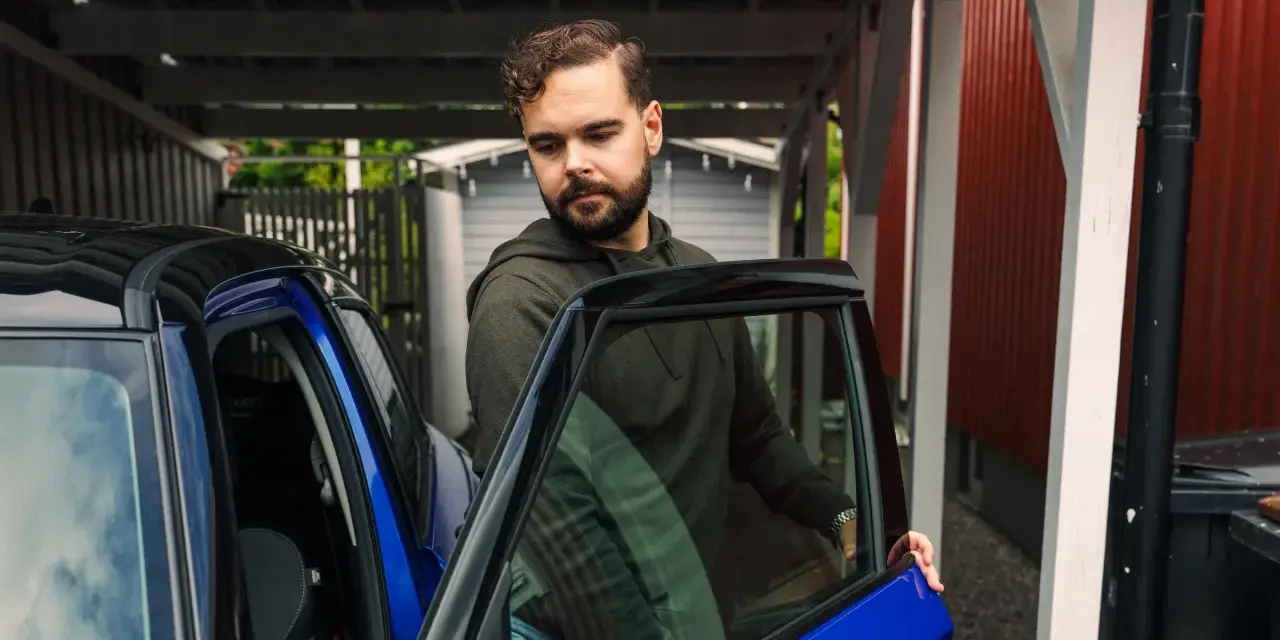 Man öppnar dörren till en blå bil. För att bilen ska hålla sig i gott skick måste man serva bilen varje år.