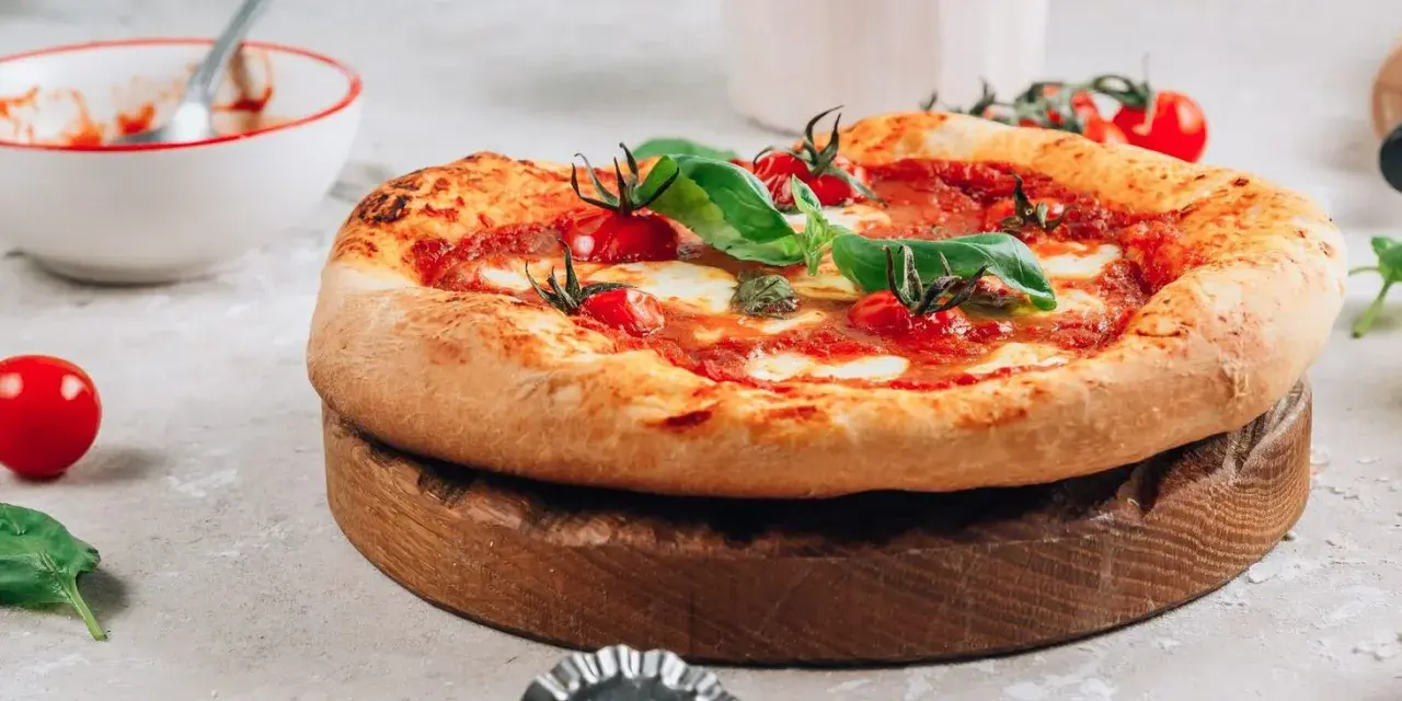 Pyszna pizza na drewnianej desce, gotowa do pokrojenia. Idealna na to, na czym piec pizze.