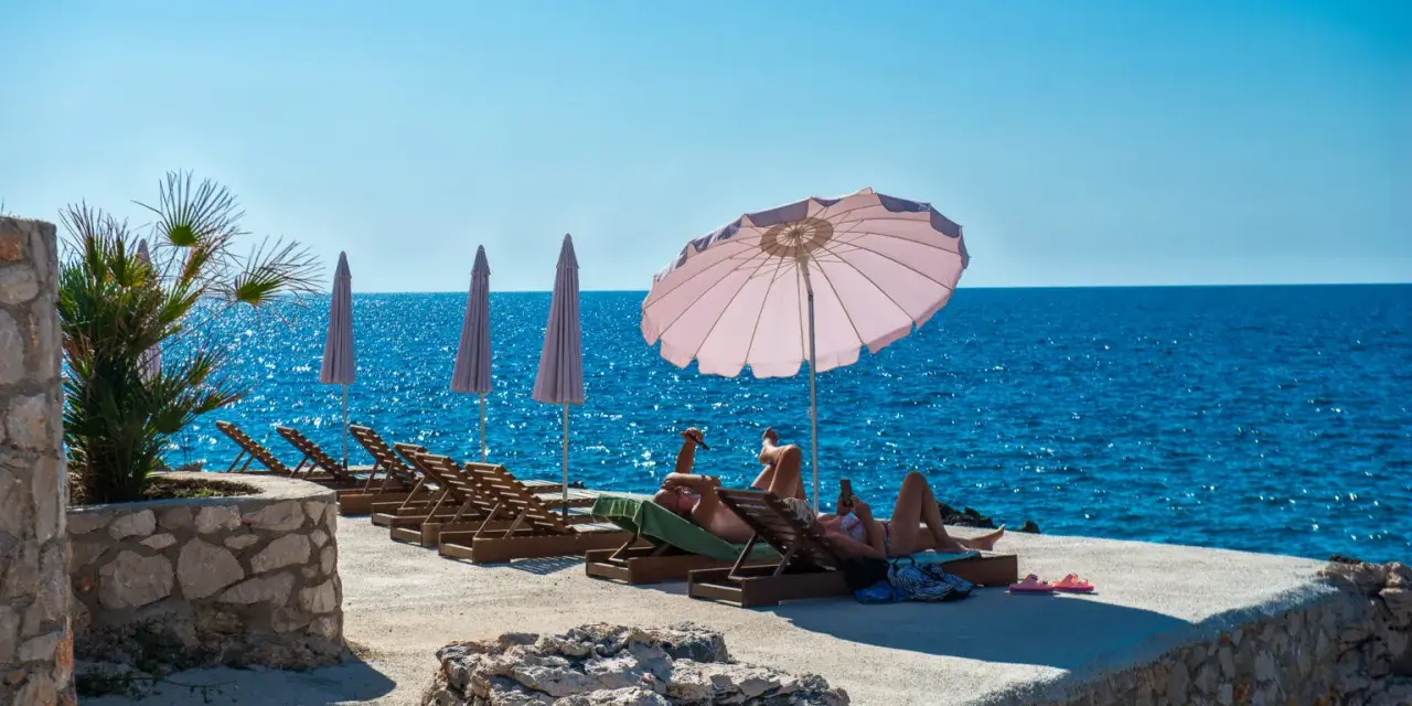 Słoneczna plaża w Czarnogórze, na co uważać? Leżaki, parasole i turkusowe morze. Idealne miejsce na relaks, ale pamiętaj o kremie z filtrem!