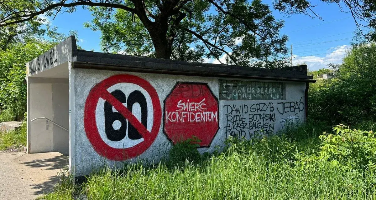Niedziela, dzień cwel, pod drzewem, z zakazem 60 i napisami na ścianie.